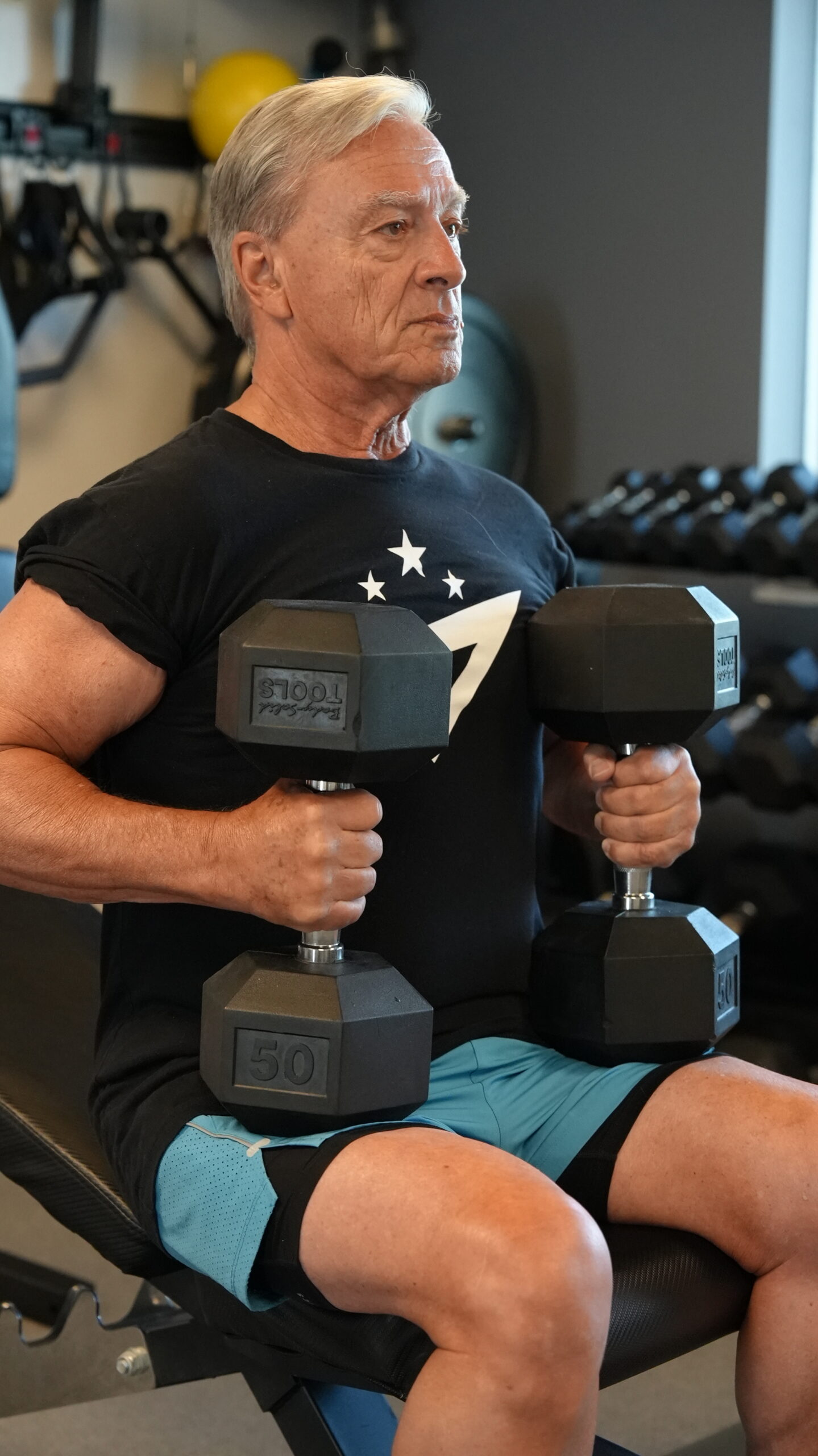 Senior member seated with two dumbbells during a coached strength session at Forge Athletics Naples FL
