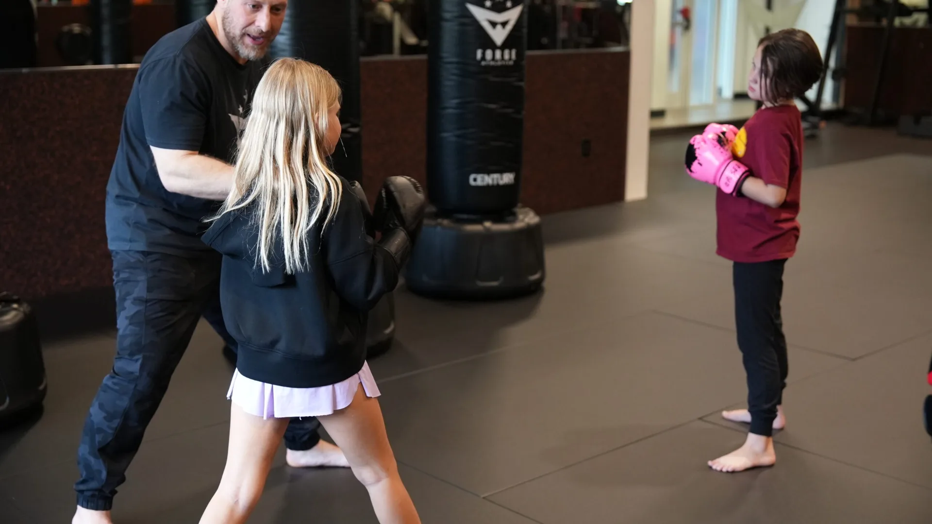 Forge Athletics coach safely training a young camper with pink boxing gloves at Naples FL summer camp
