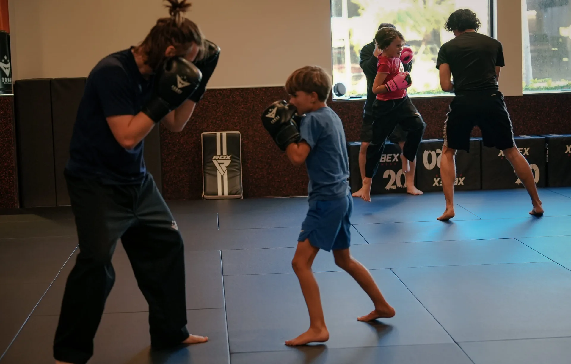 Full-day summer camp Naples FL — coach guiding a young camper at the heavy bag at Forge Athletics