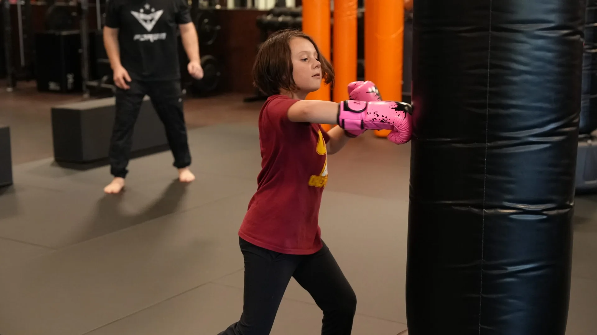 Girl wearing pink gloves training at the heavy bag at Forge Athletics Naples FL summer programs for kids