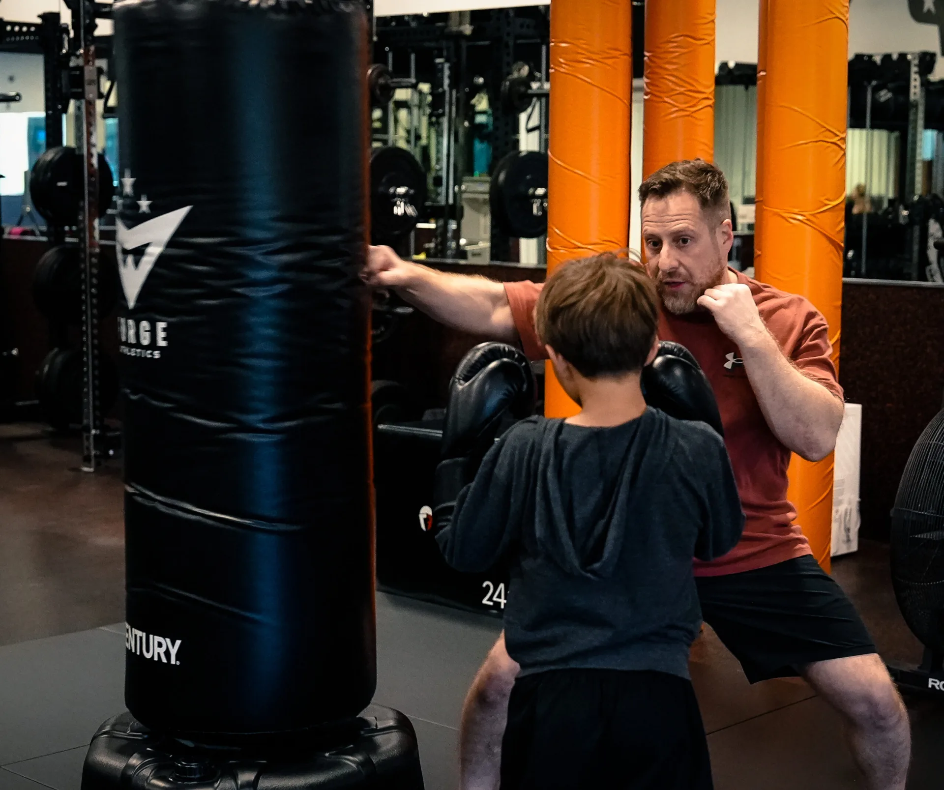 Forge Athletics coach working one-on-one with a young camper at the heavy bag in Naples FL