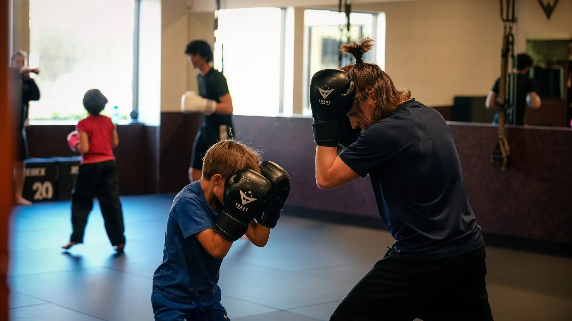 Kid kicking a heavy bag at Forge Athletics summer camp in Naples FL — active alternative to screen time