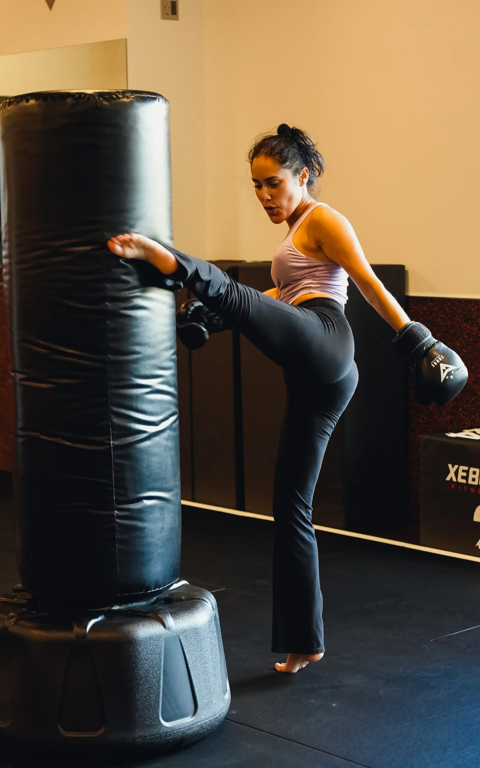 Naples woman throwing a high kick on the heavy bag at Forge Athletics — martial arts for women
