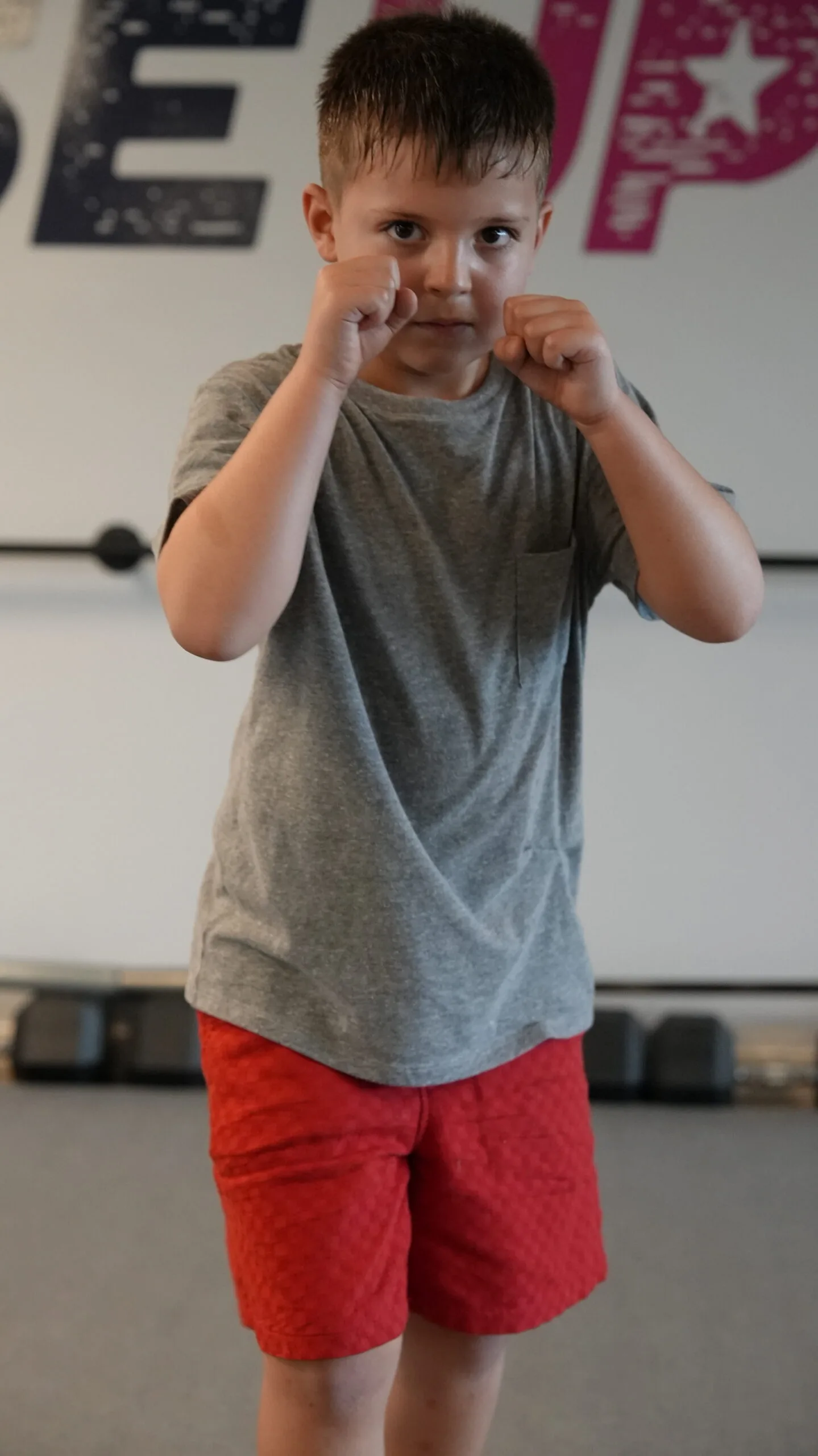 Young boy learning proper boxing stance at Forge Athletics summer camp for 6-year-olds in Naples FL
